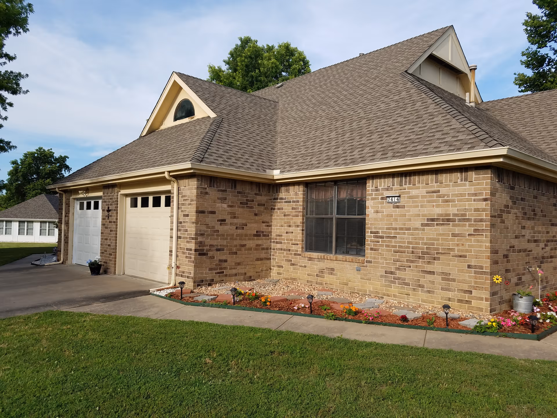 Brick building with gabled roof, two garage doors, and landscaped front yard.