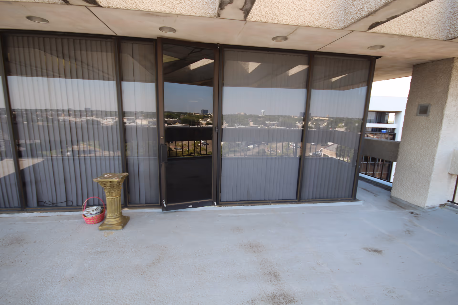 Balcony area of a senior living facility with sliding glass doors and blinds.