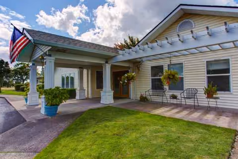 Exterior view of Trustwell Living at Evergreen Place with front entrance, flag, and porch seating.