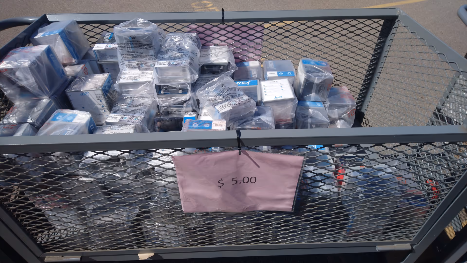 Outdoor cart filled with boxed HoMedics products and a pink $5.00 sign.