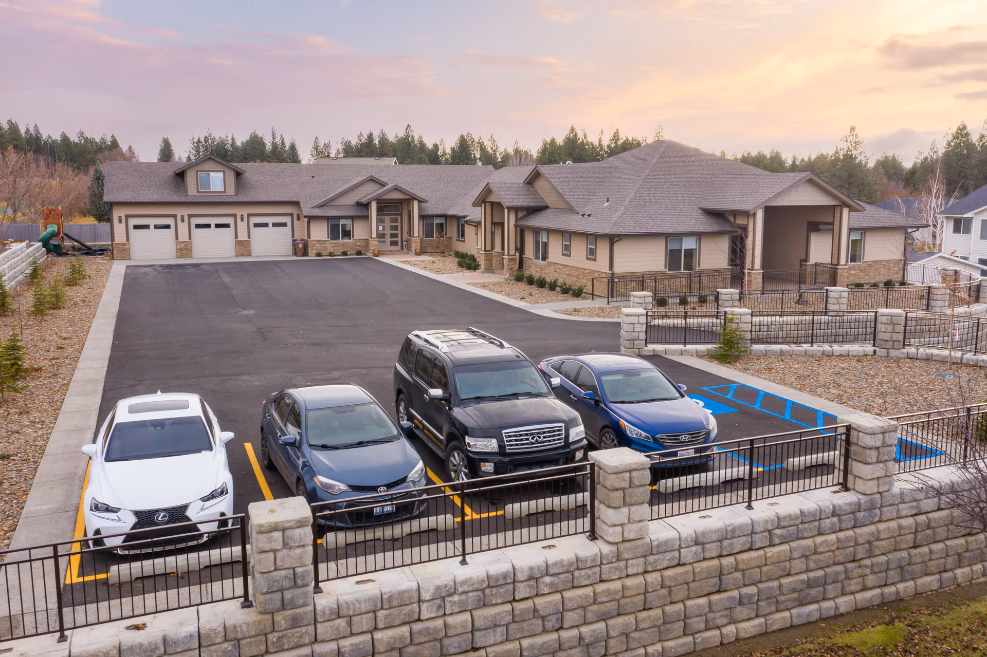 Exterior view of Providence Senior Home front with parked cars, driveway, and stone fence.