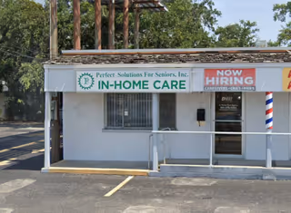 Small white storefront with IN-HOME CARE sign and Now Hiring banner outside.