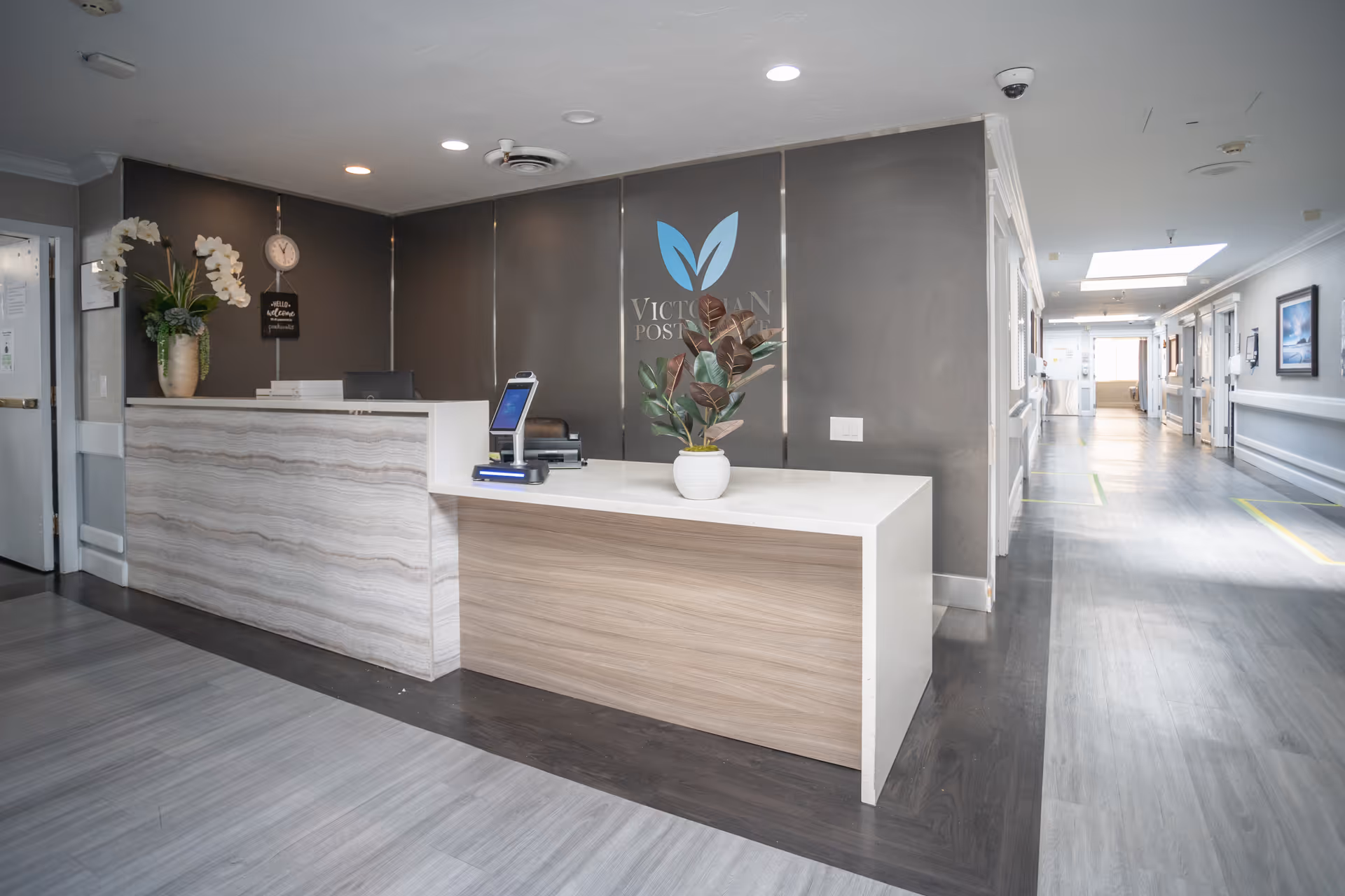 Reception desk in a modern hallway of Victorian Post Acute, logo on wall.