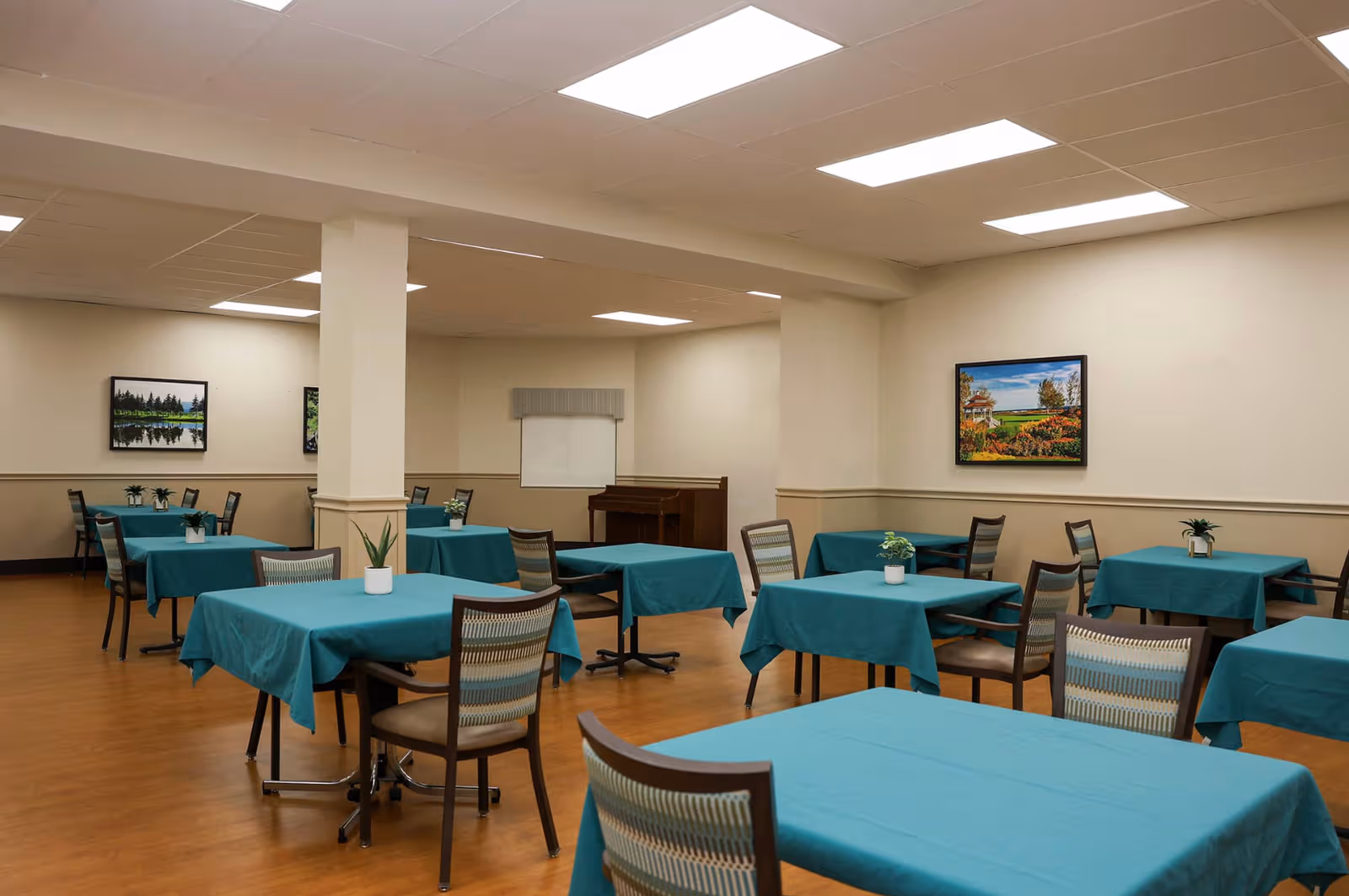 Bright dining room at Pleasant Ridge Healthcare Center with teal tablecloths and plants.