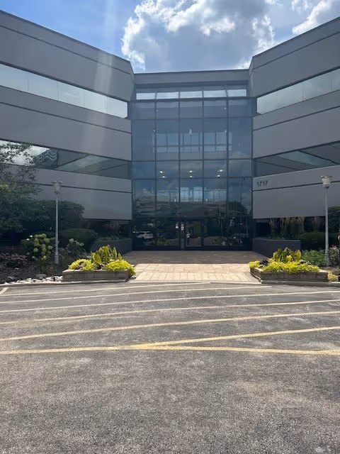Front view of Three Oaks Hospice building with glass entry and landscaped walkway.