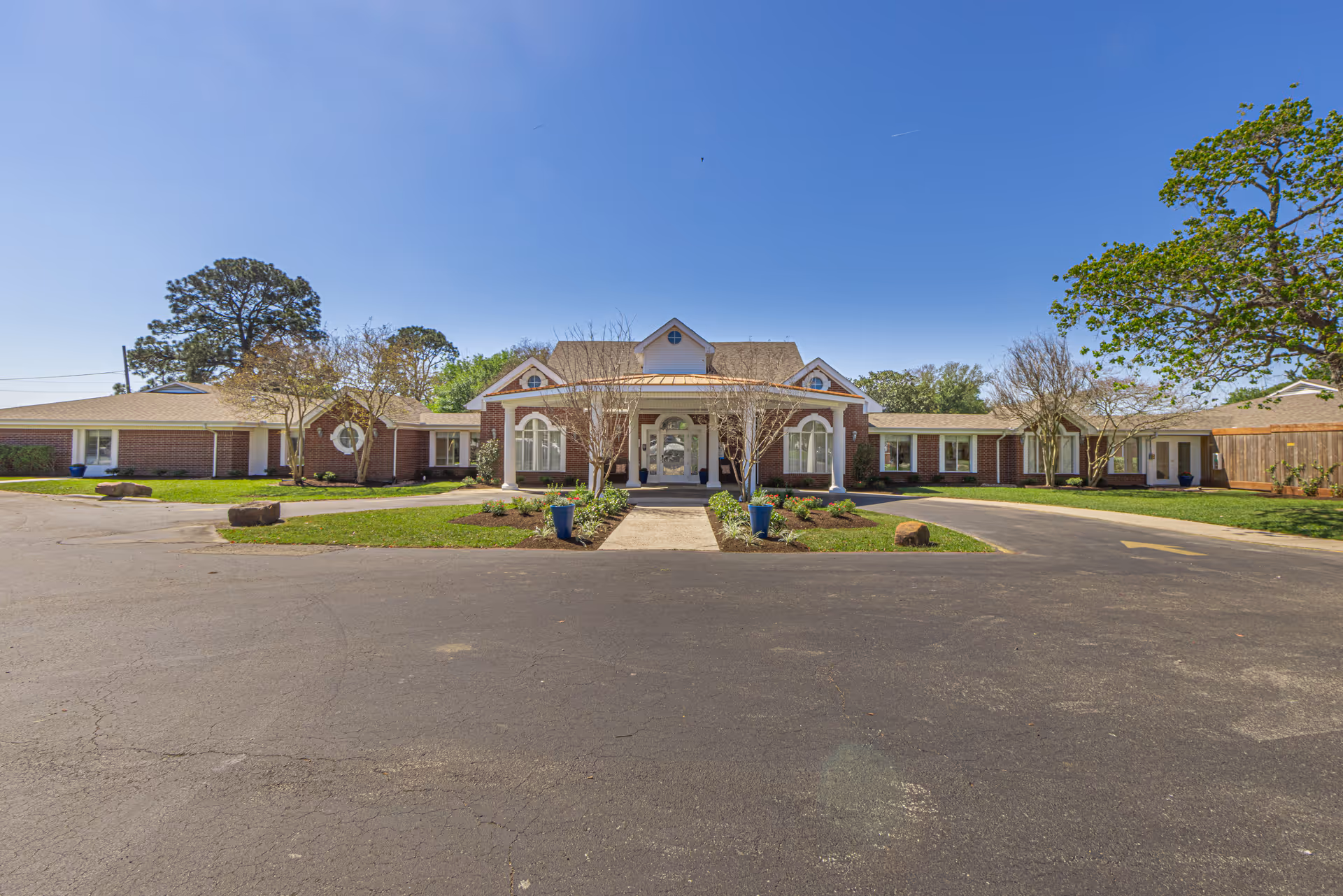 Single-story brick senior living facility with central entrance and landscaped front grounds.