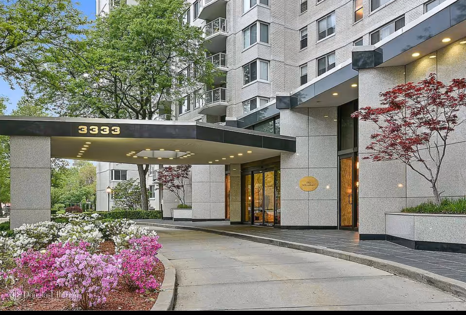 Exterior view of a modern senior living building entrance with glass doors and landscaping.