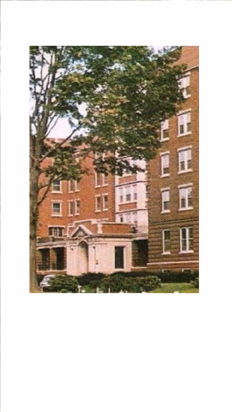 Brick senior living building front with entrance and trees.
