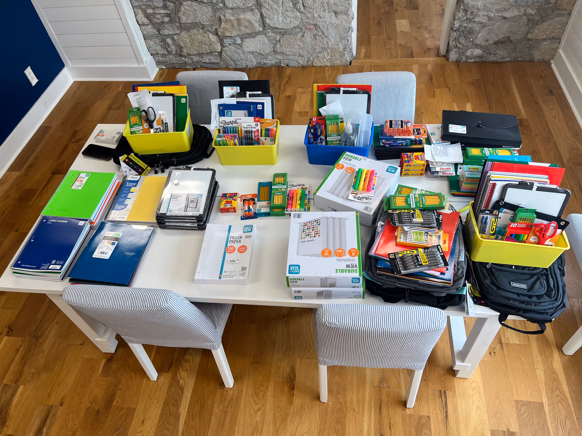 Overhead view of a table filled with notebooks, folders, and assorted school supplies.