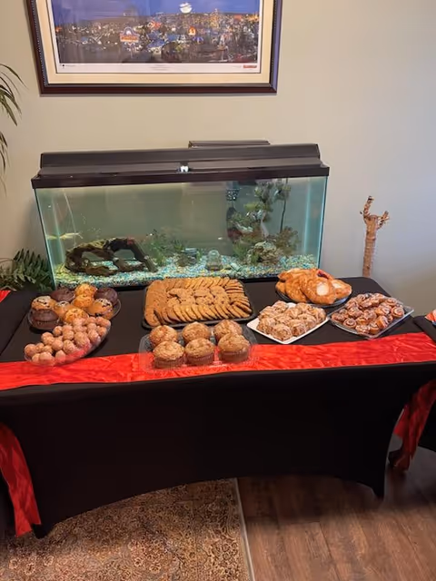 Table with assorted pastries and an aquarium in a staged dining area.