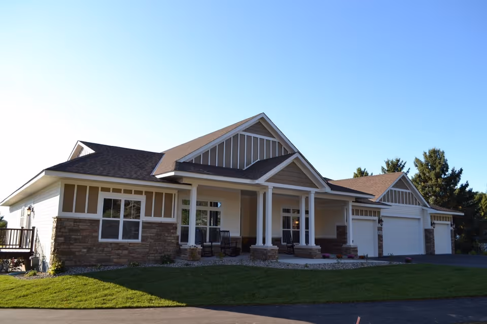 Single-story senior living facility with stone accents and a multi-garage front under blue sky.