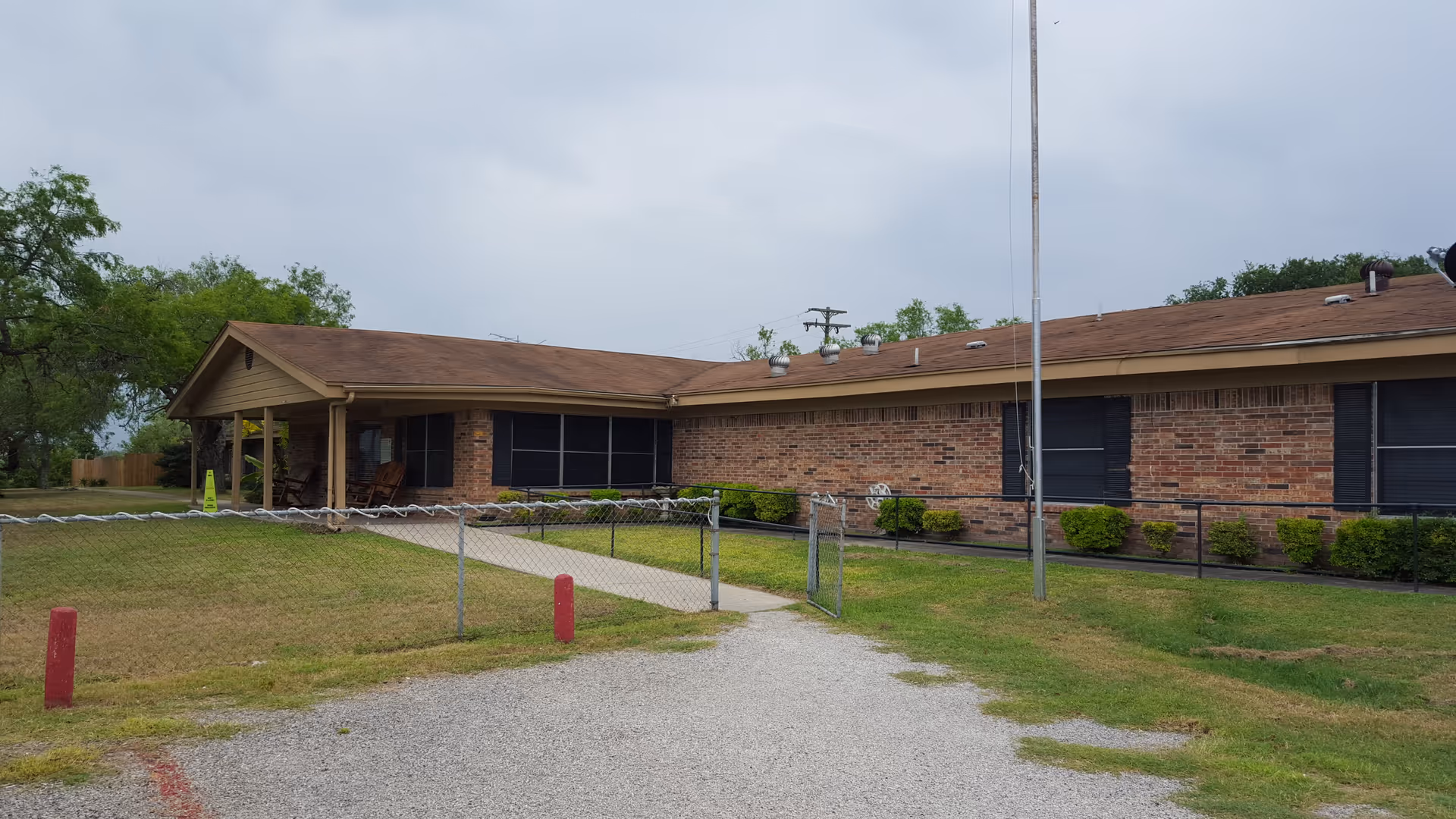 Kenedy Health and Rehabilitation exterior: single-story brick building with walkway and fence.