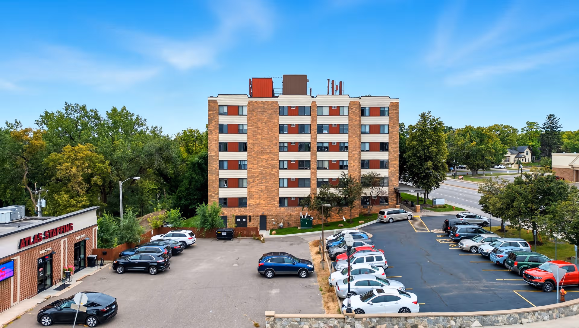 Exterior view of a multi-story senior living building with a parking lot and surrounding trees.