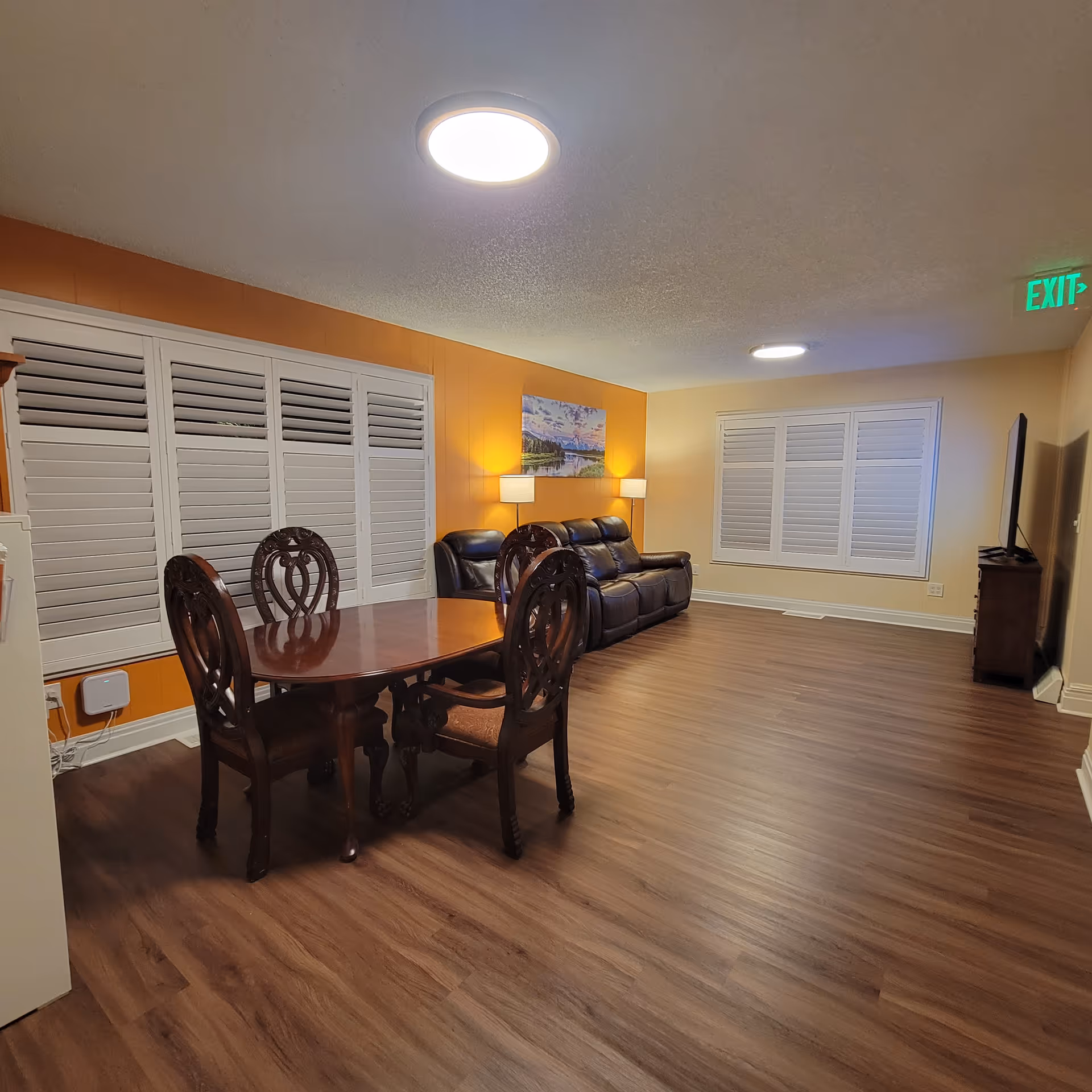 Interior common area with dining table, leather sofa, and orange accent wall.