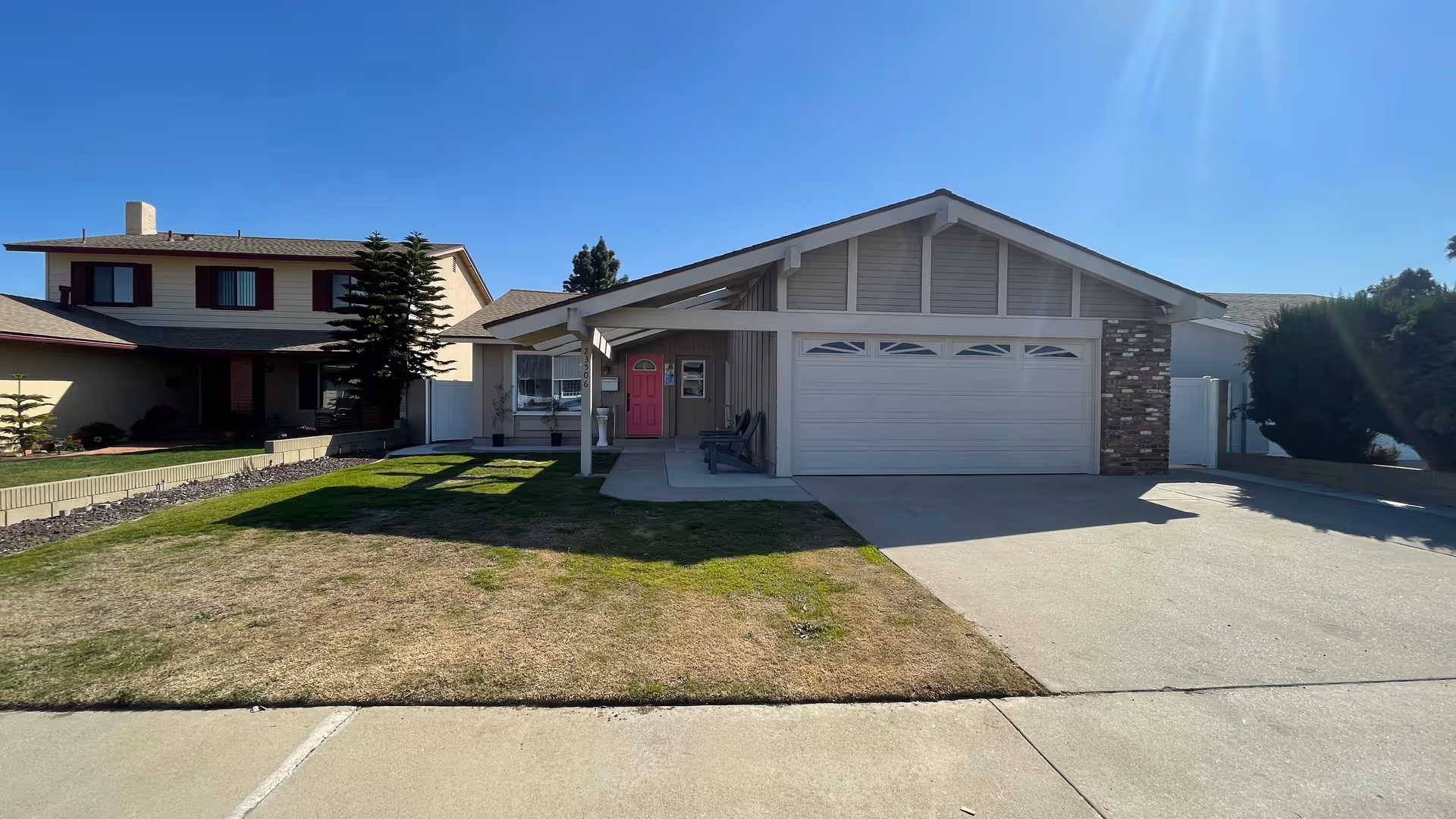 Single-story home with a pink front door, attached garage, and manicured lawn.