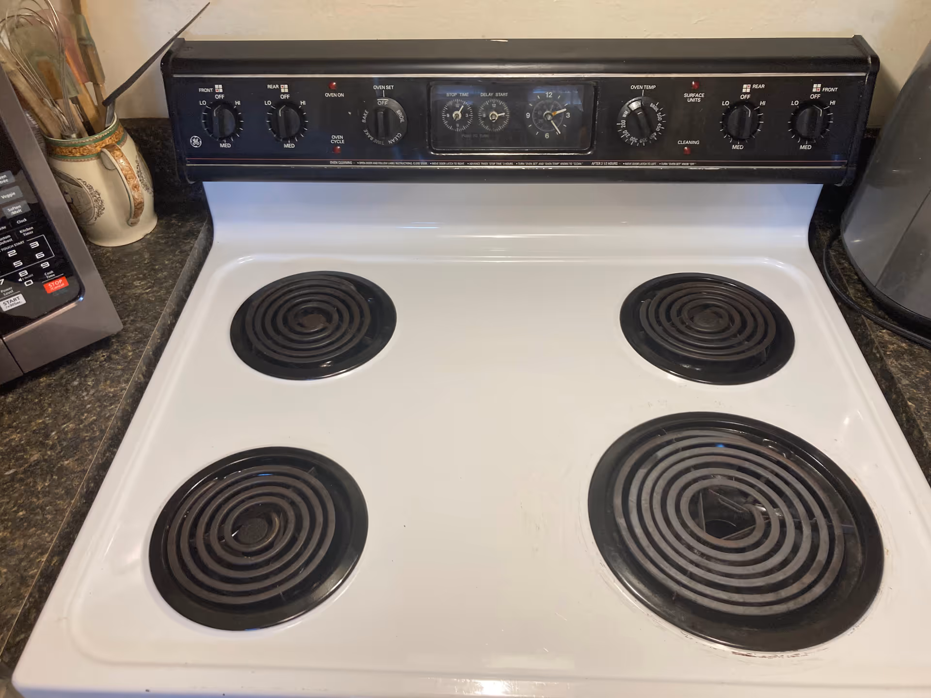 A white electric stove with four coil burners sits on a kitchen counter.