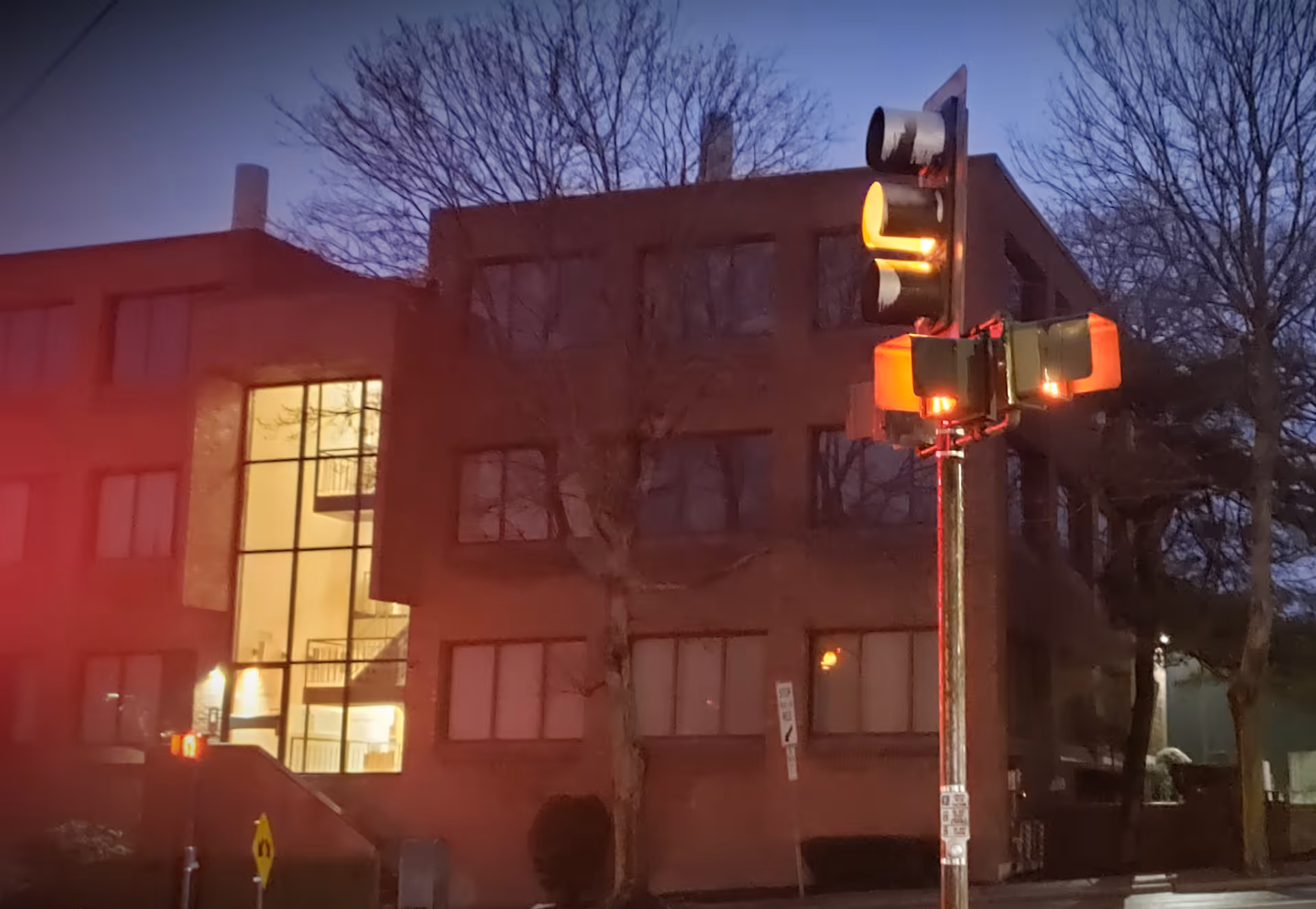 Night exterior view of Ezra Home Care, LLC building with lit entrance and street traffic light.