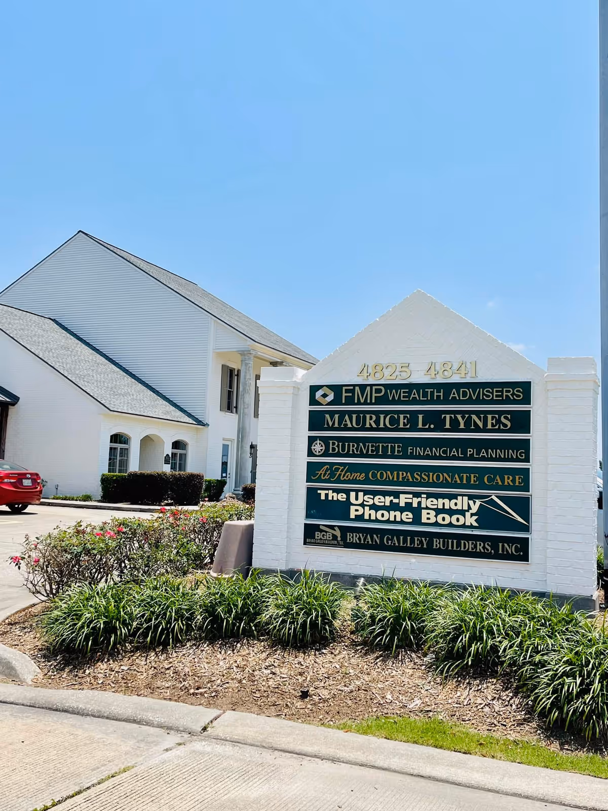 Exterior of At Home Compassionate Care facility with a large front sign and landscaping.