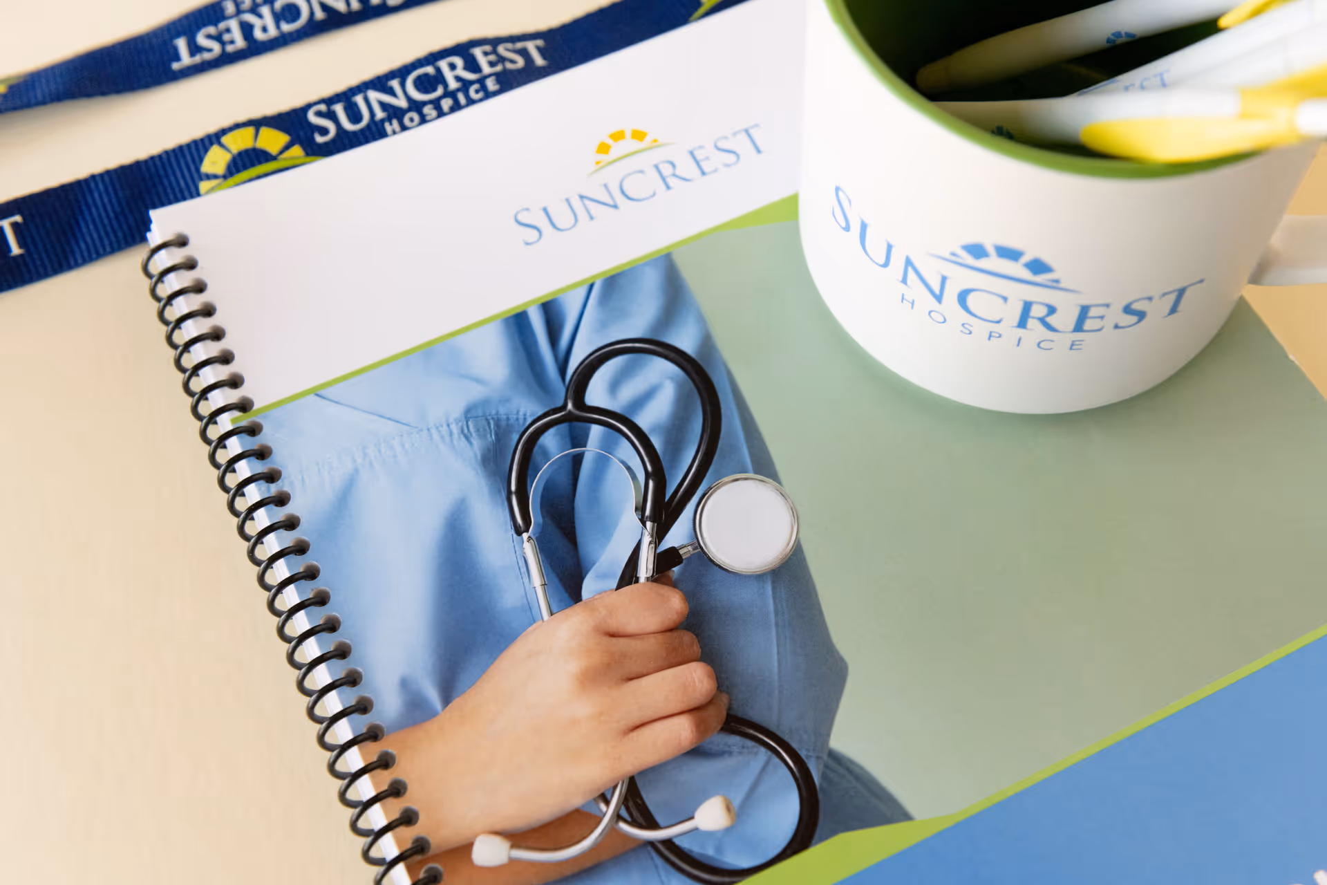 Close-up of Suncrest Hospice-branded documents, stethoscope, and a cup with pens.