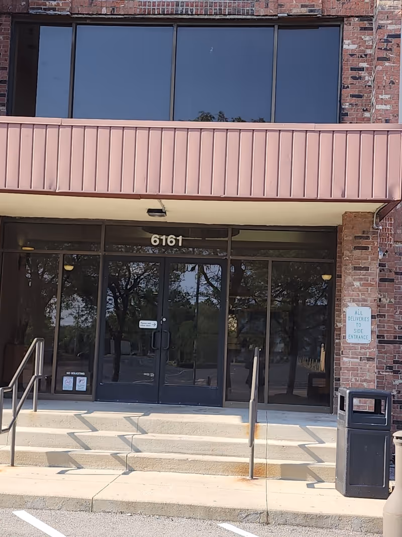Front entrance of a brick building with glass doors and stairs, 6161