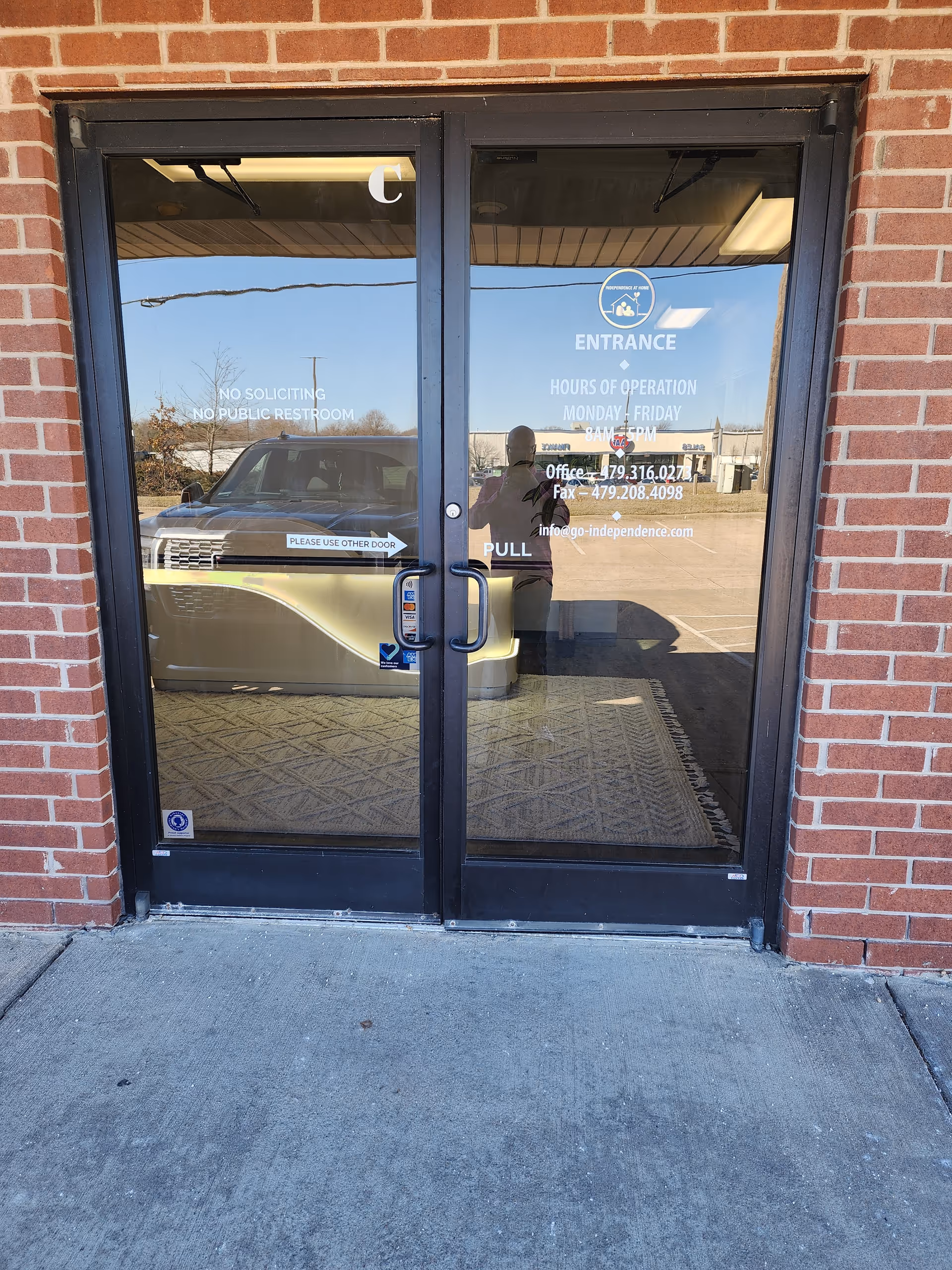 Glass double doors with brick exterior marking the building entrance and a reflected car.