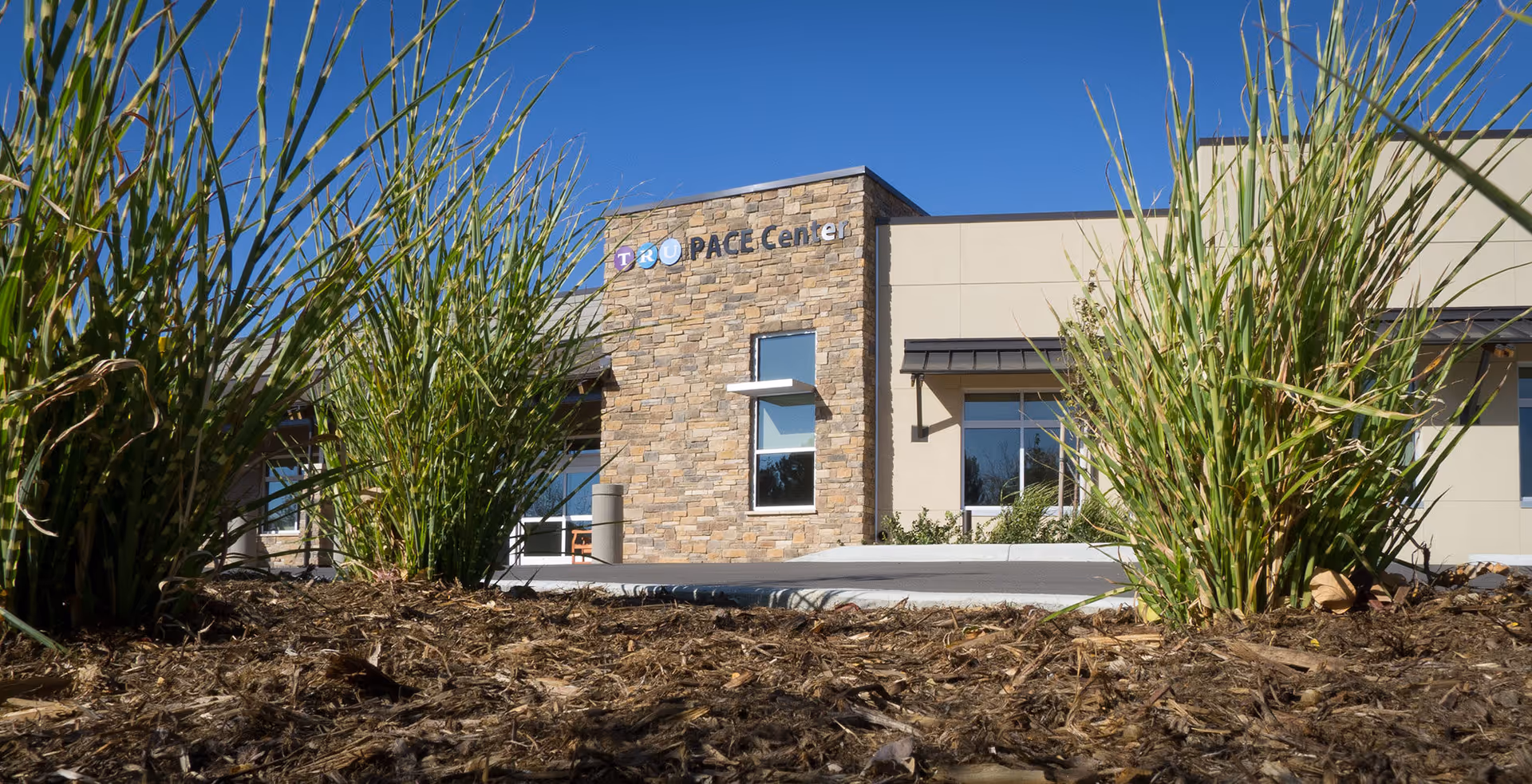 Exterior view of TRU PACE Center with a stone facade and tall grasses.