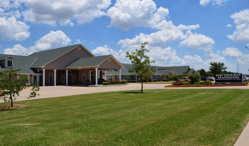 Exterior view of Southwest Mansions Senior Independent Living building with lawn and parking.