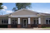 Front view of Maple Manor Village facility with white columns and glass entry doors.
