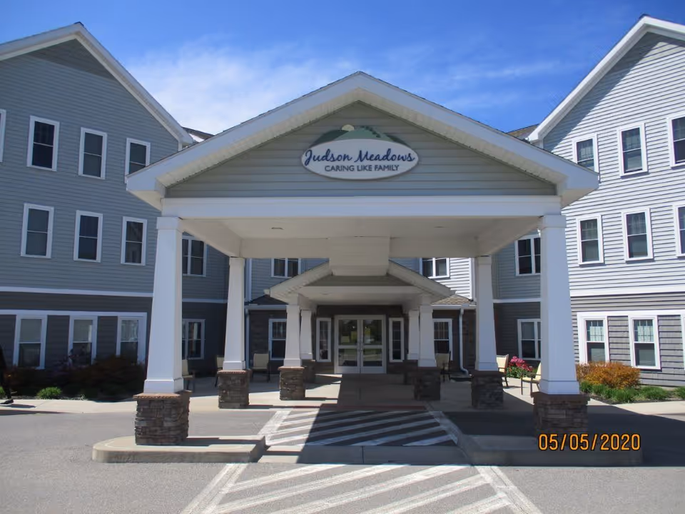 Judson Meadows assisted living entrance with a covered portico and gray building exterior.