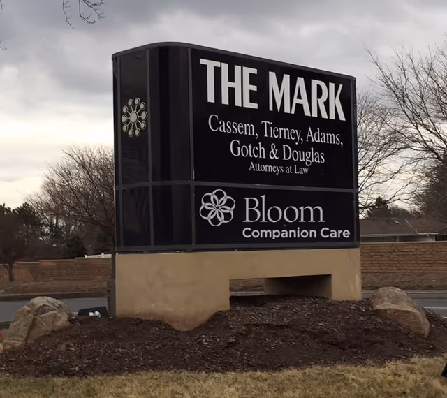 Large outdoor black sign for The Mark and Bloom Companion Care