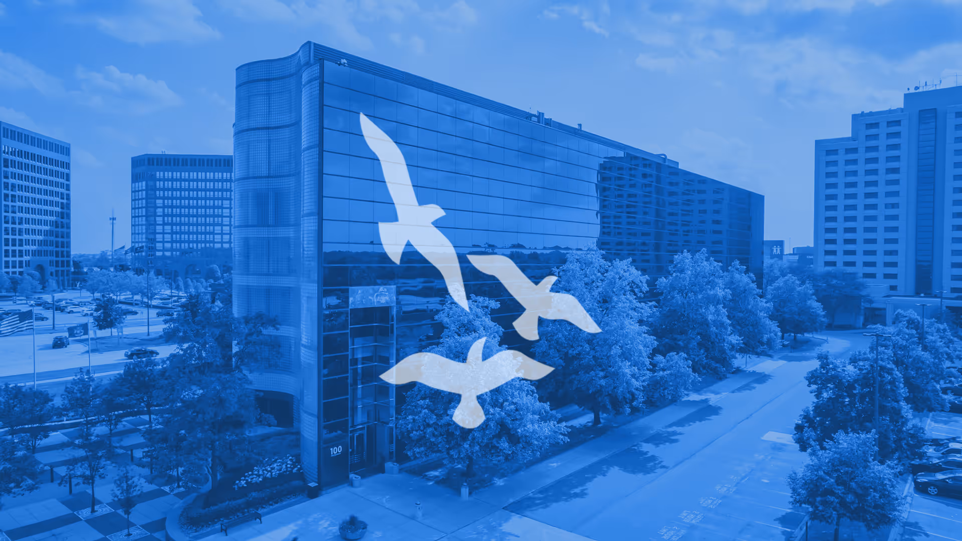 Blue-tinted aerial view of a glass-front building with white bird graphics.