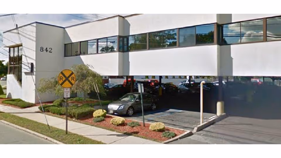 Exterior view of a modern senior care building with cars in the driveway.