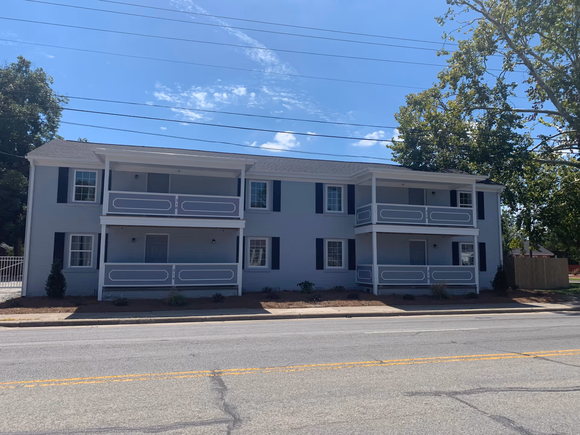 Two-story blue building with white balconies along a street, no people visible.
