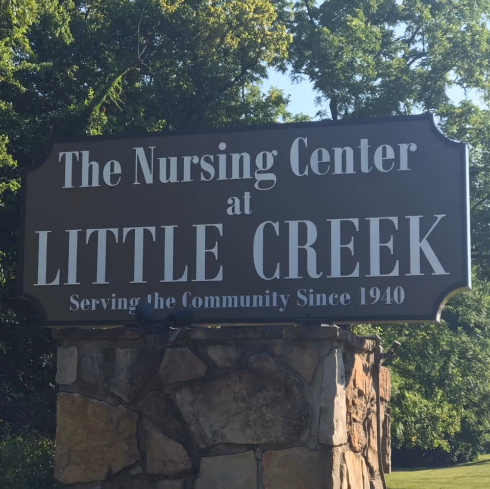 Large outdoor sign reading The Nursing Center at Little Creek mounted on a stone base.