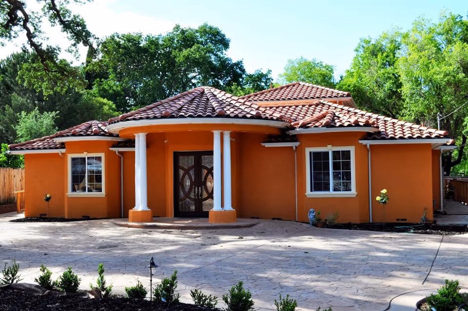 Orange stucco care home with tile roof and white columns at entrance