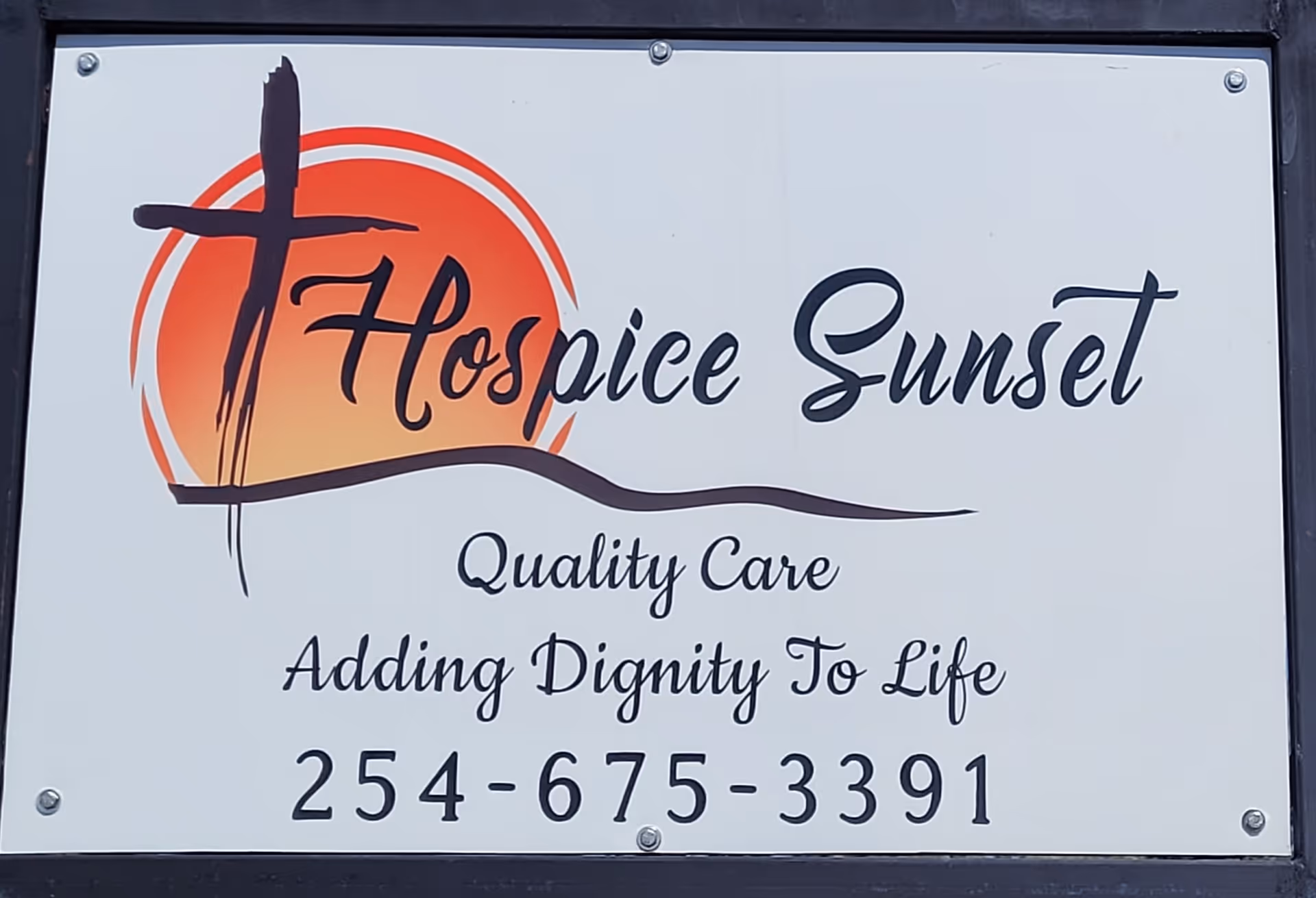 Outdoor sign reads Hospice Sunset with logo and phone number on exterior wall.