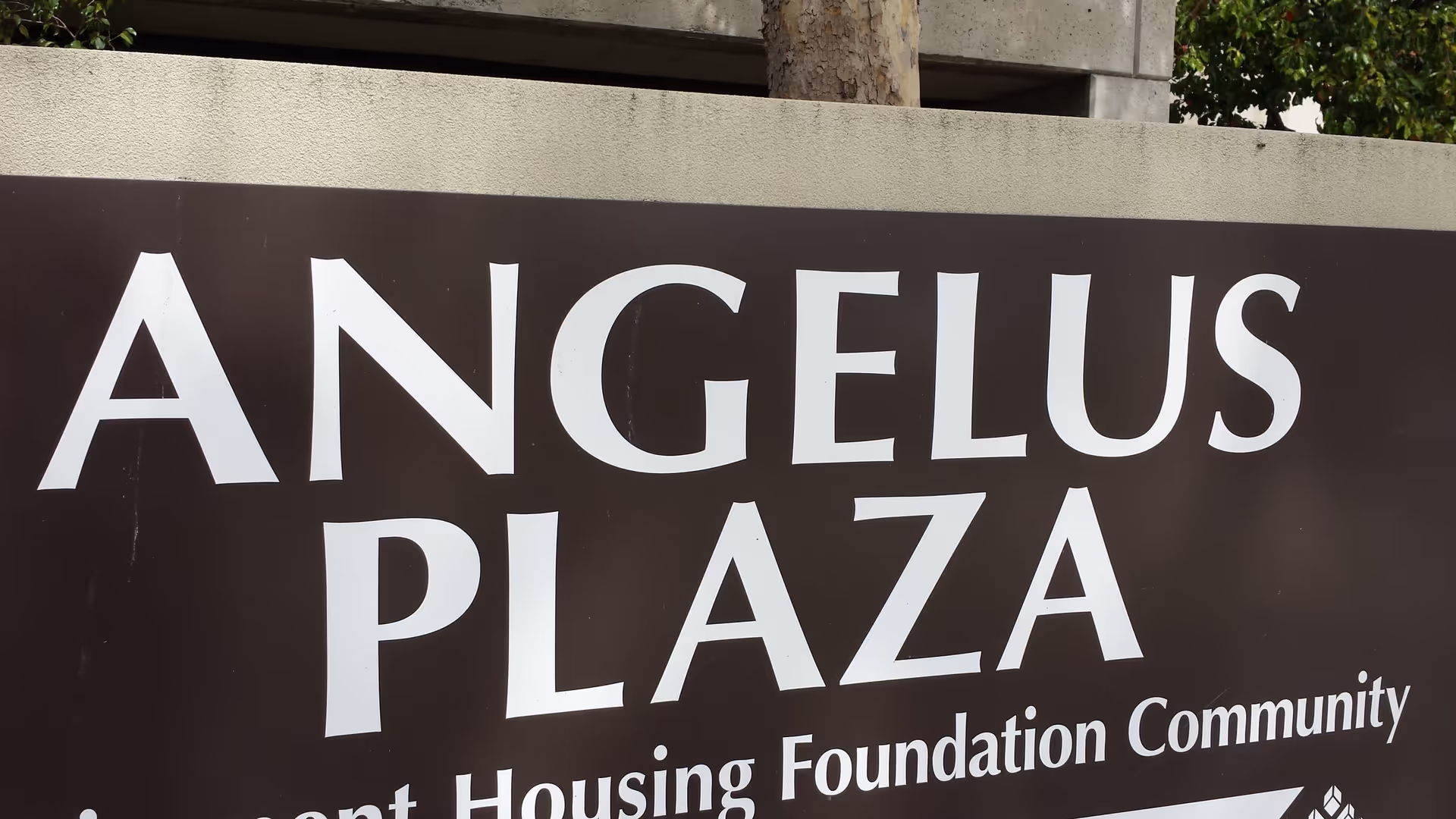 Large brown sign reading ANGELUS PLAZA in front of the building.
