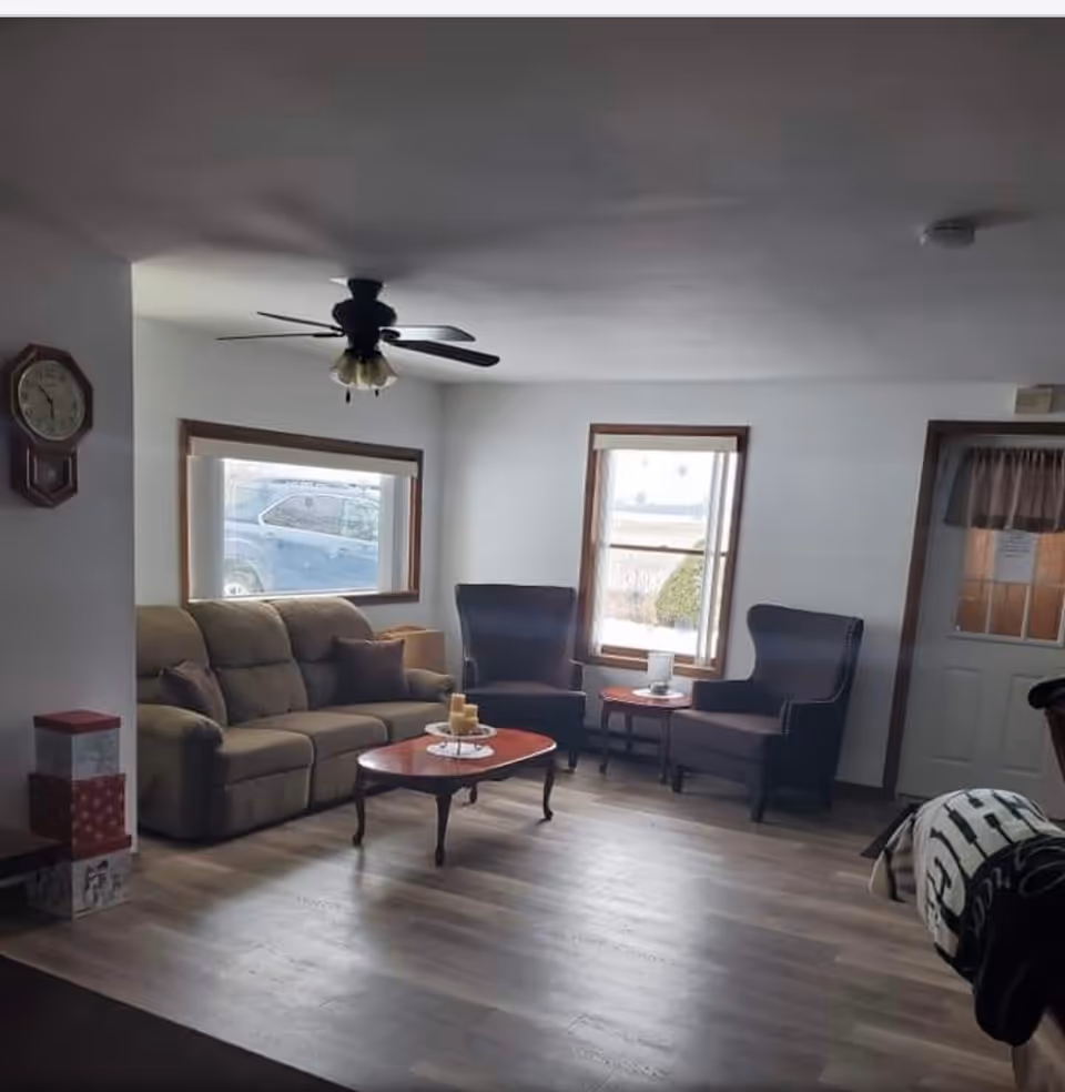 Cozy living room with sofa, two chairs, coffee table, and windows.