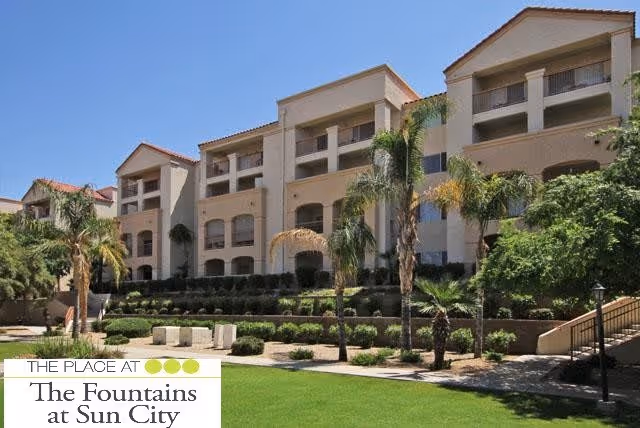 Exterior view of a multi-story senior living facility building with balconies, surrounded by palm trees and well-maintained landscaping under a clear sky.