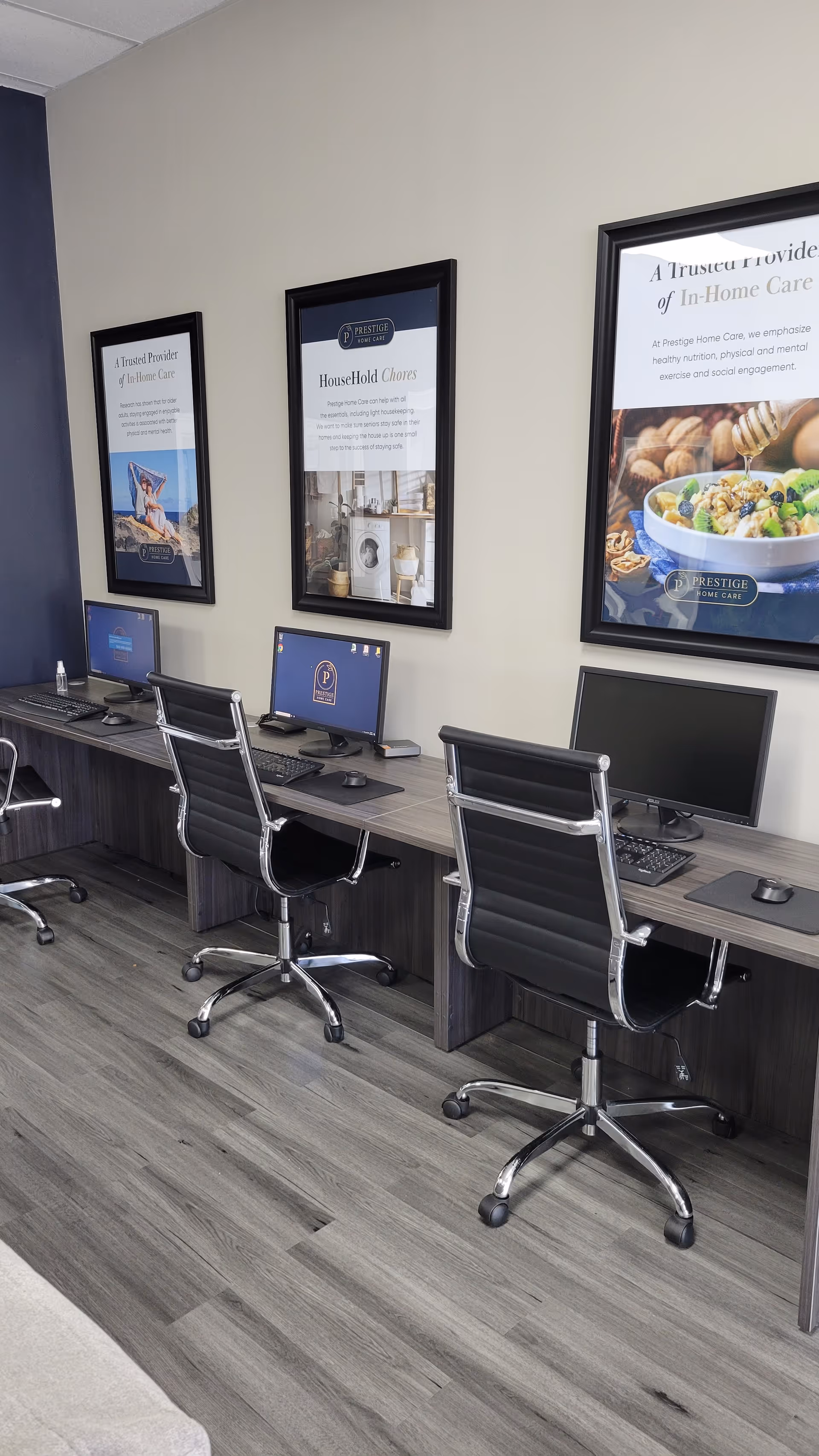 Office workstation row with computers and framed posters on a beige wall.