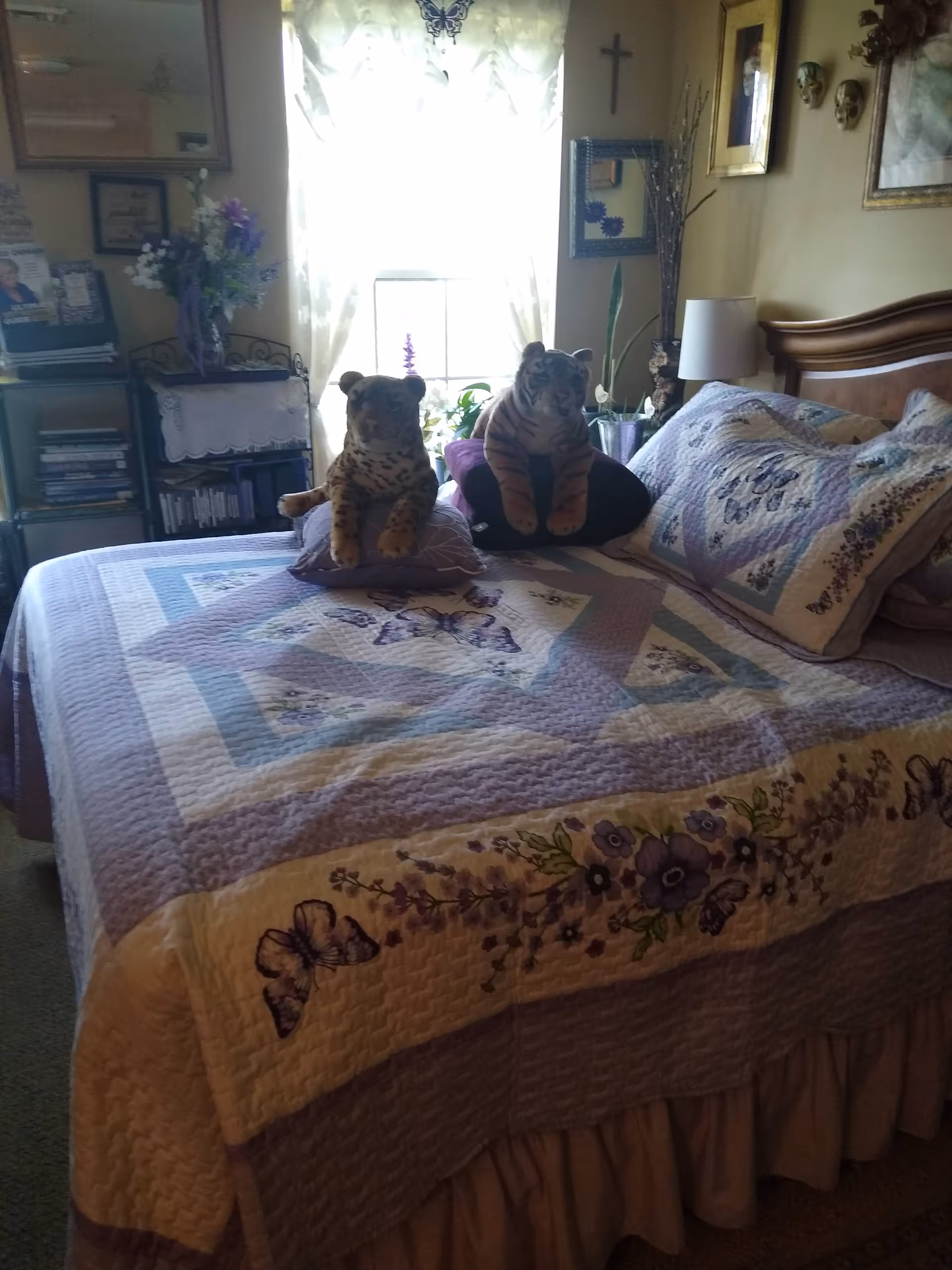 Bedroom scene with a quilted bed, two tiger plush toys, and wall decor.