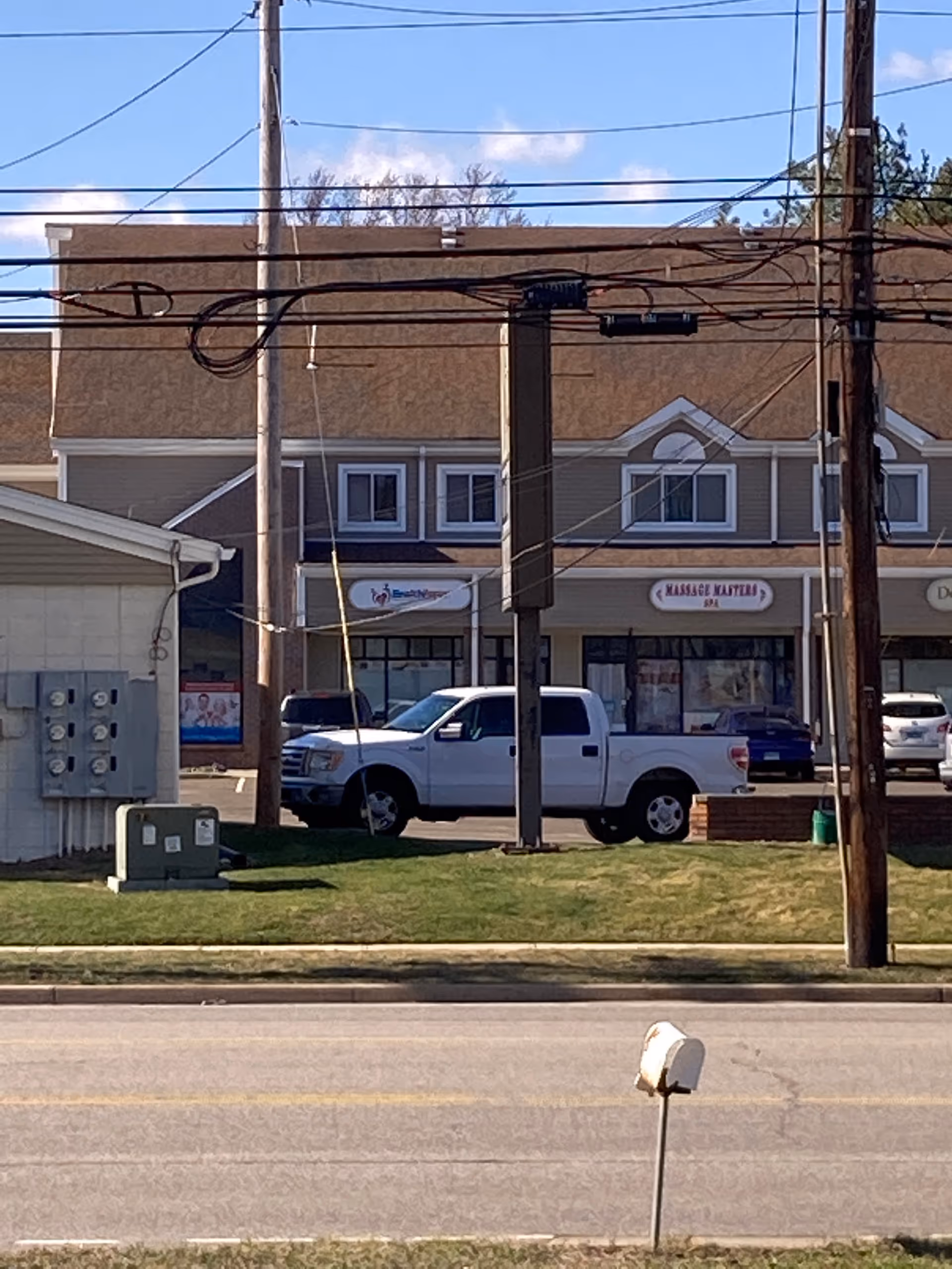 Street view of storefronts with a white pickup truck parked along the curb.