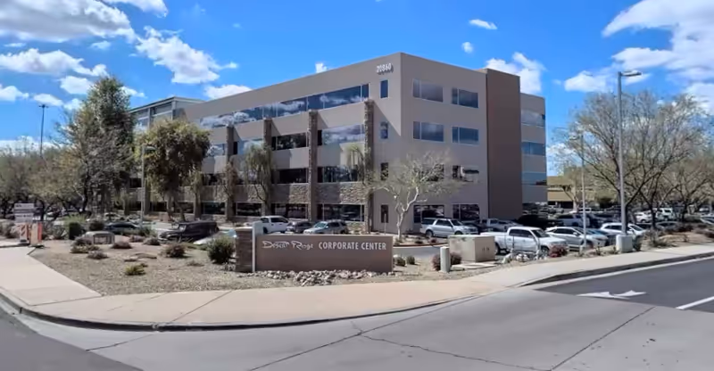 Front view of a modern three-story office building with a parking lot.