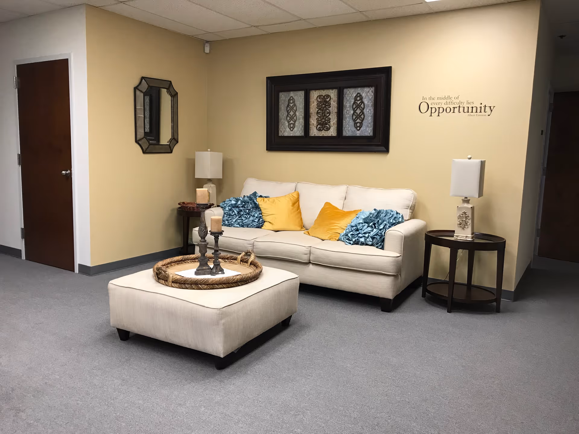 Cozy lounge area with beige sofa, teal and yellow cushions, lamps, and wall art.