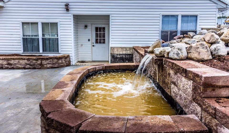 Exterior view of Nova Springs Assisted Living with a stone-bordered fountain near the entrance