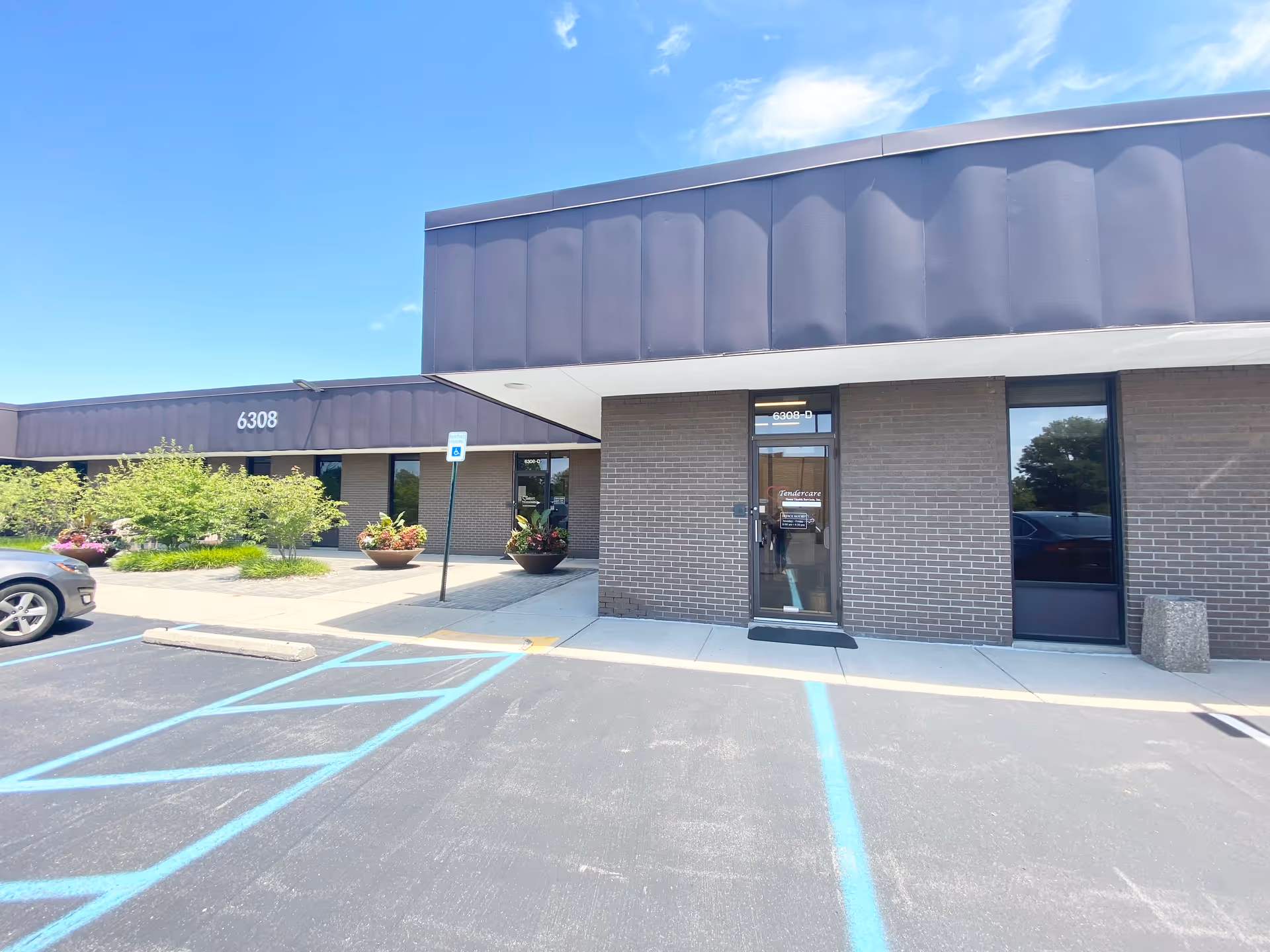 Tendercare-branded senior care building with entrance, parking, and landscaping under a clear sky.