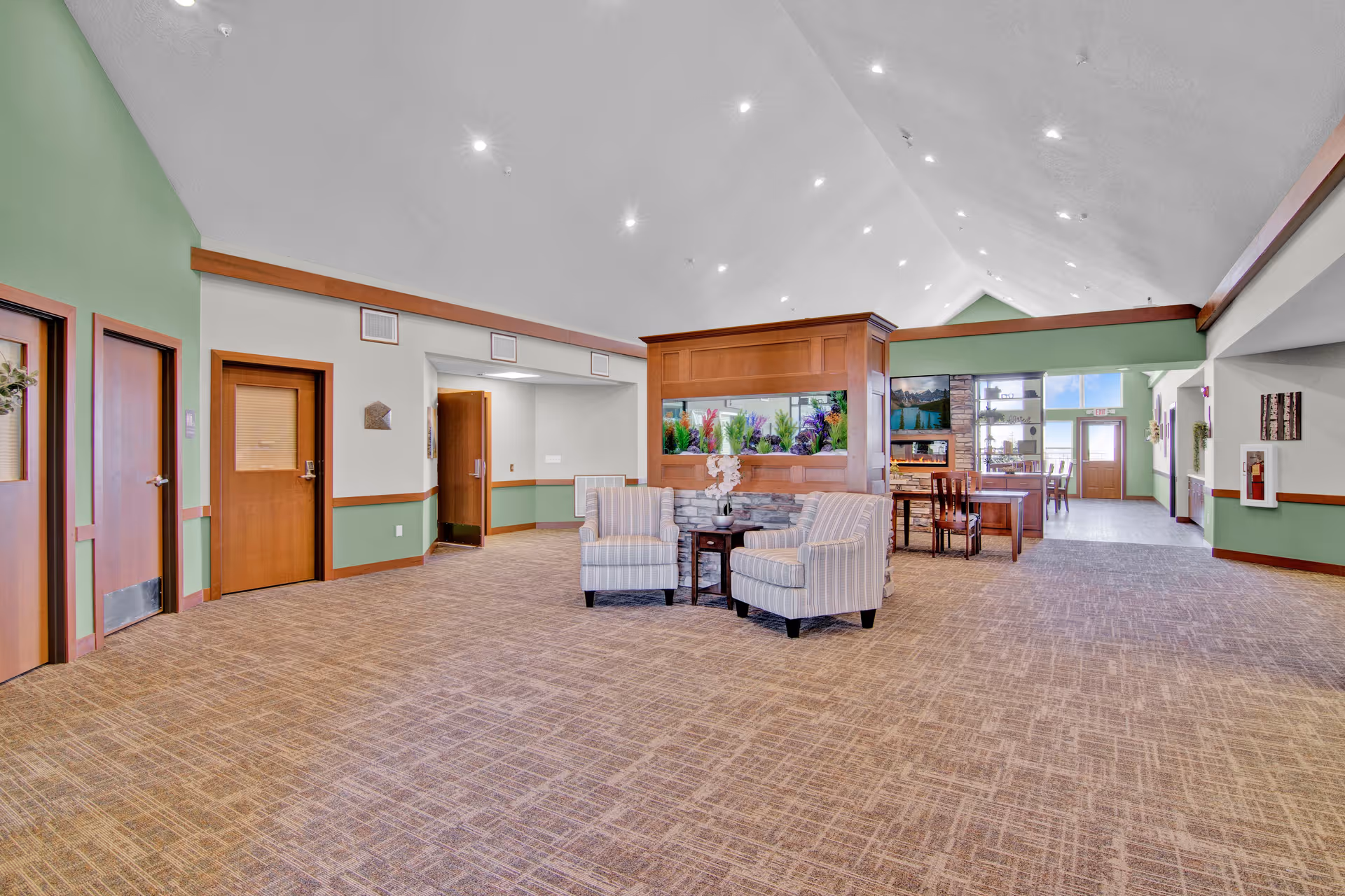 Spacious lobby with seating group, aquarium centerpiece, and a dining area in the background.