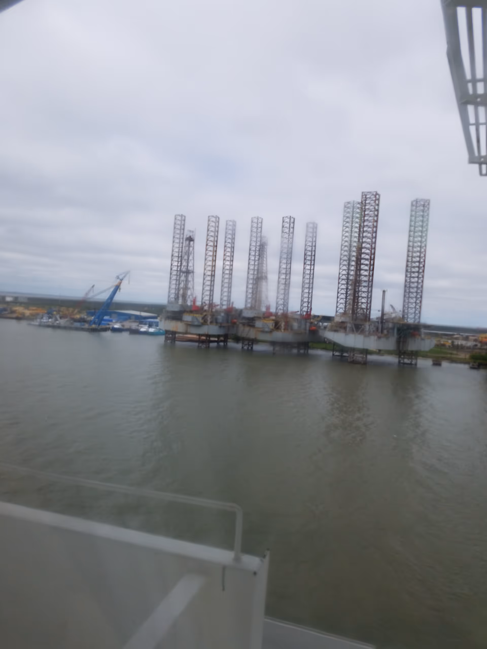 Overcast harbor scene with tall metal frame structures on pilings.