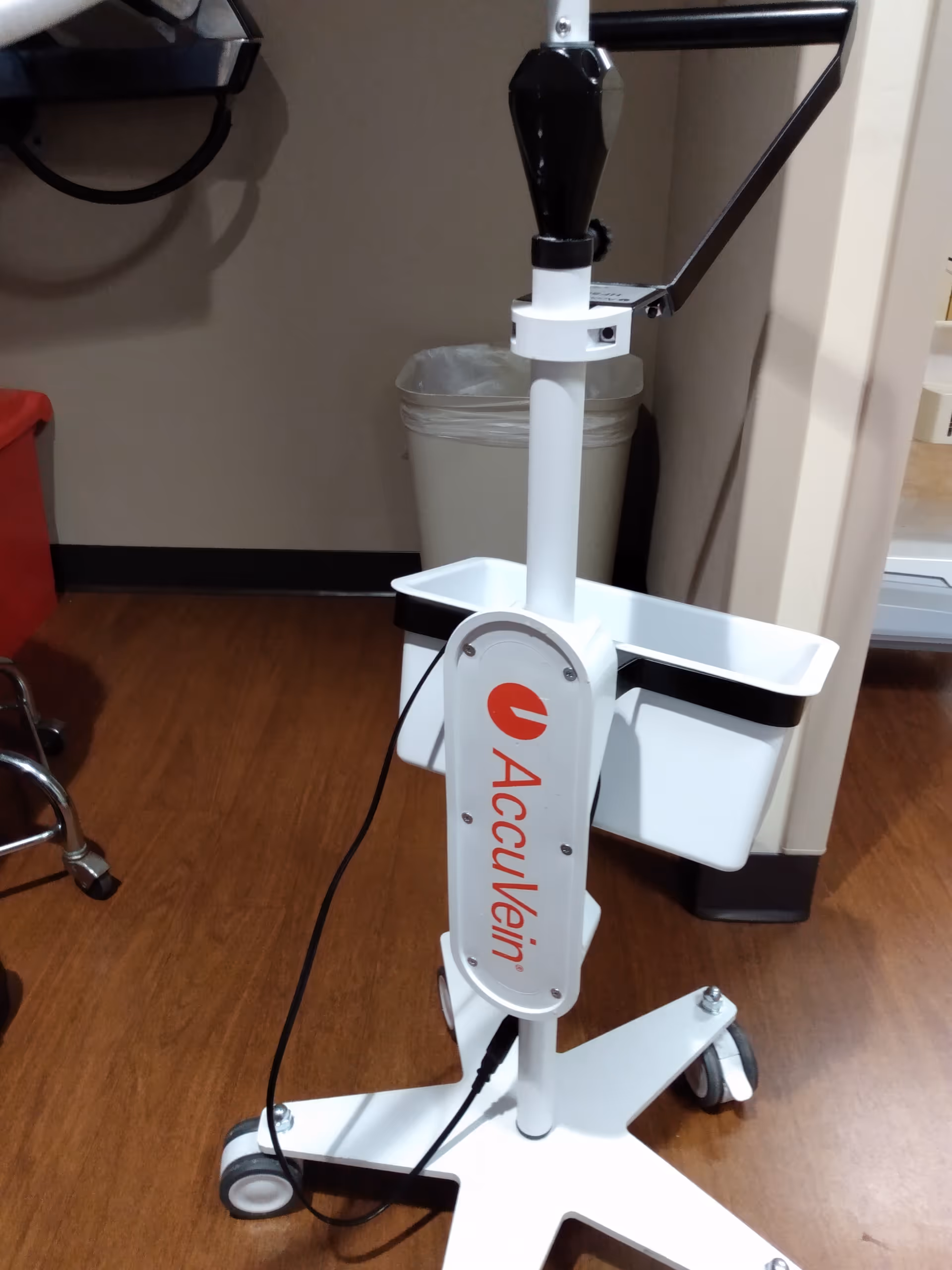 AccuVein vein visualization device on a wheeled stand in a clinical room.
