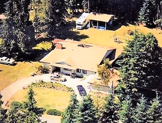 Aerial view of a single-story residential building surrounded by trees and a yard.